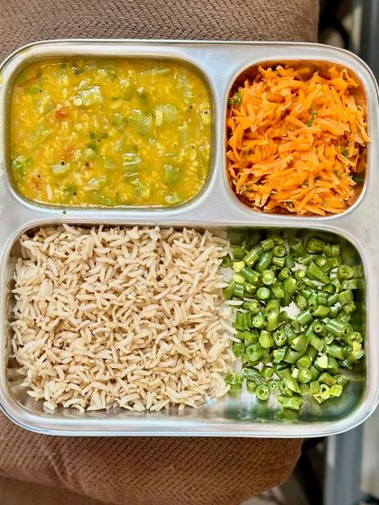 A simple yet vibrant plate of brown rice, dal, and a tricolor mix of carrots and beans, showcasing the beauty of simple ingredients.