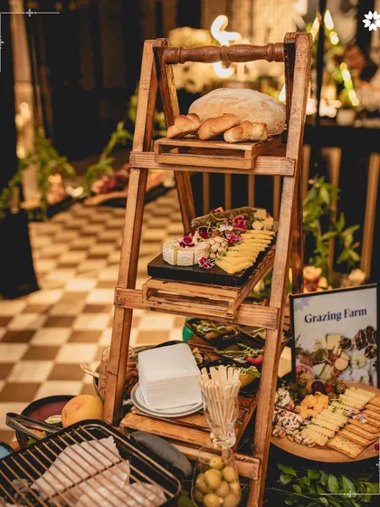 A "Grazing Farm" setup featuring a rustic ladder display for breads and cheeses. This innovative presentation style turns a simple food station into a decorative and memorable feature of the event.