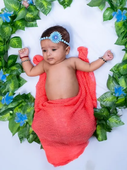 A newborn baby posed safely within a beautiful, leafy wreath prop. This type of styled newborn photography creates artistic and memorable portraits.