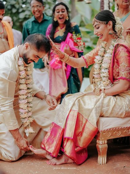 A beautiful moment from a Hindu wedding ceremony, where the bride playfully blesses the groom, surrounded by the happy faces of their family.