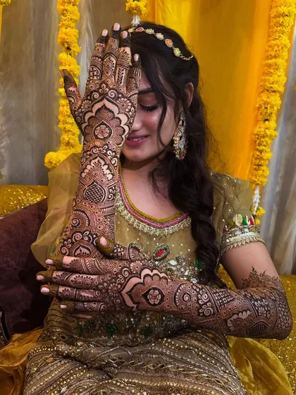 A classic shy bride pose. This shot beautifully captures both the bride's emotion and the stunning detail of her henna.