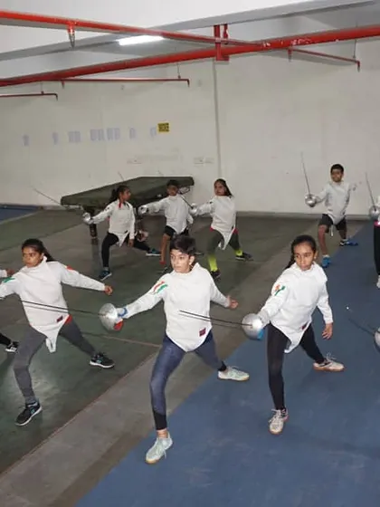 Discipline in motion. A group of our students practices their lunges in unison, a fundamental move in fencing. We focus on perfecting these core techniques together, ensuring every fencer develops proper form and muscle memory.