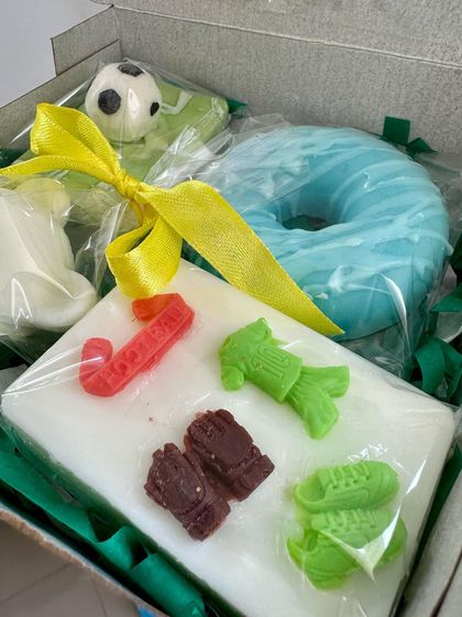 A custom soap box curated for a young football fan. This gift set includes a football field soap, a donut soap, and a teddy bear soap, showing the endless possibilities for themed gifts.