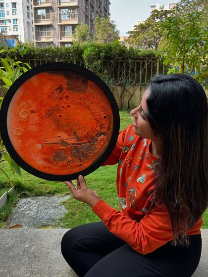 Holding the finished, unlit Mars lamp. This shows the scale of the piece and the deep, rich colors of the acrylic paint on the textured surface.