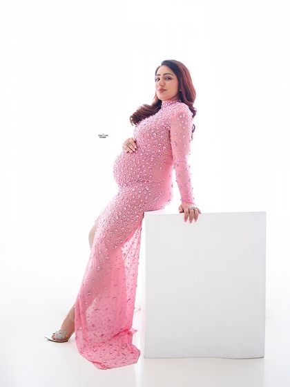A modern and chic portrait. This mamma looks stunning in a pink embellished gown, leaning against a simple white block prop.