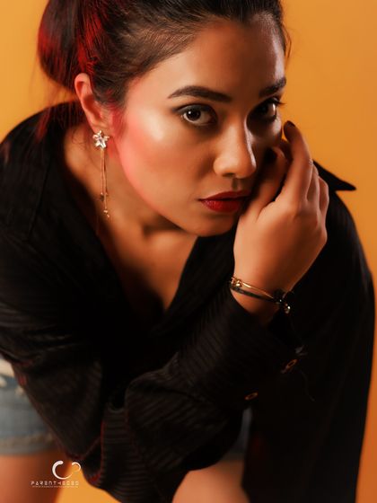 A close-up portrait with an intense gaze. The warm lighting and simple styling put the focus entirely on the subject's expression and mood.