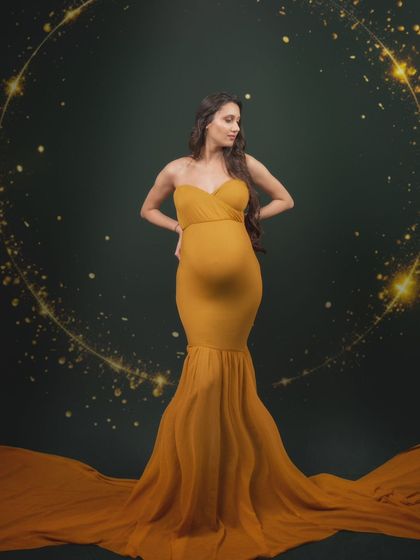 Glowing like the golden hour. This stunning mumma shines bright in a custom golden gown against a dark green backdrop and sparkly sphere.