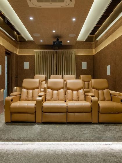 A frontal view of the home theatre, showing the two-tiered seating arrangement and the ambient cove lighting.