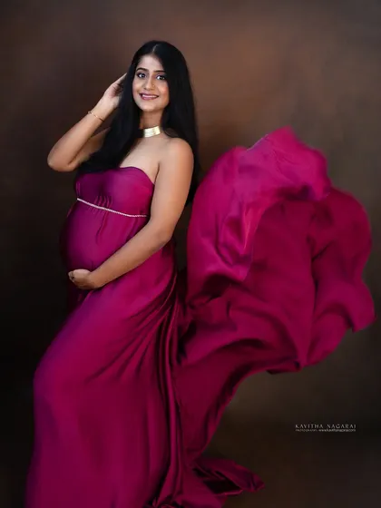 A smiling mother-to-be in a flowing gown, looking radiant and happy. The movement of the fabric creates a dynamic and beautiful maternity portrait.