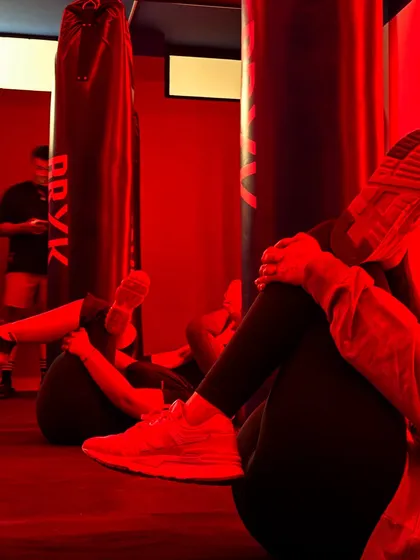 The red-lit ambiance of our studio during a cool-down. Members stretch and relax after a tough group class, sharing the space and the sense of accomplishment.