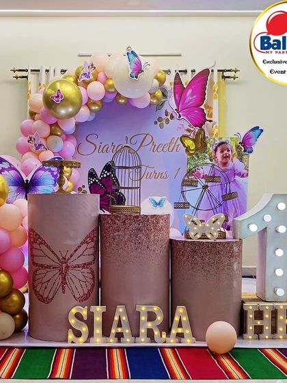 A lovely butterfly-themed first birthday with a photo of the birthday girl. The pink and gold balloon arch and butterfly details create a warm and celebratory feel.