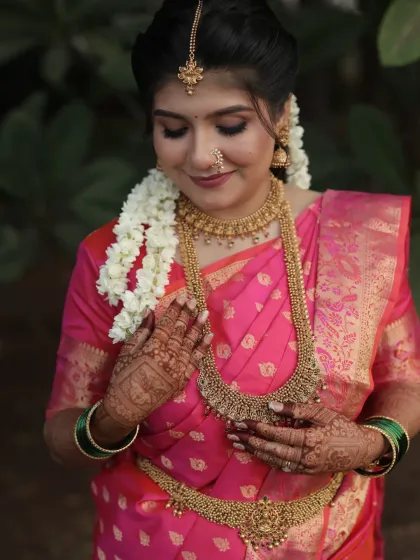 The bride Madhumita's engagement look in a beautiful pink silk saree, with traditional temple jewellery.