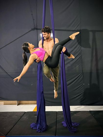 A closer look at a duet pose, showing the connection and balance between two aerialists as they work together on the silks.