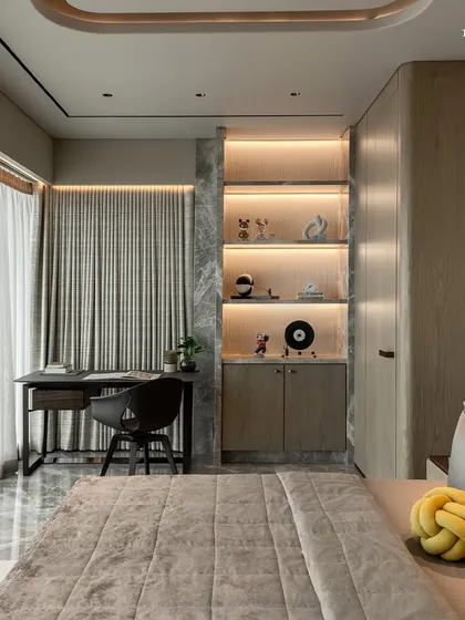 A detail of the bedroom in the 3300 sq. ft. Shivaji Park home, showing the study nook and integrated shelving. The design uses white marble, wood veneers, and textured walls, juxtaposed with Italian furniture to anchor the tonal palette in calm and continuity.