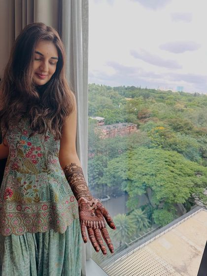 A serene moment with the bride admiring her henna design by the window.