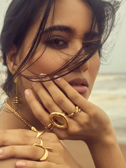 A close-up of the windswept look, with soft, natural makeup that enhances the model's features against the beach backdrop.