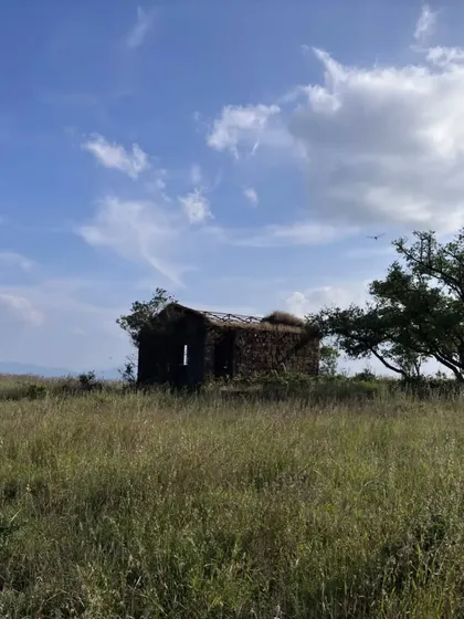 An old, abandoned stone structure in the middle of the grasslands.