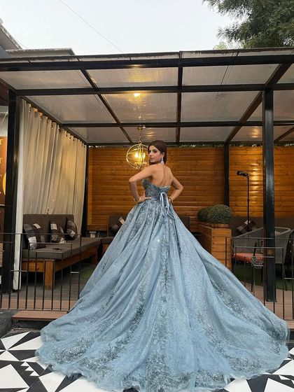 The back view of the strapless blue ball gown, showing off its long, dramatic train and delicate corset lacing. This is a perfect dress for making an unforgettable exit.