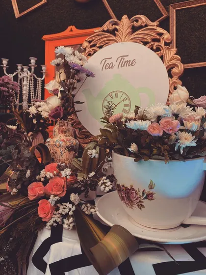 "It's Tea Time!" A detail from the Alice in Wonderland theme, featuring a giant teacup filled with flowers set against a vintage-style framed sign.
