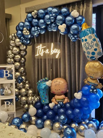 A close-up of the "It's a boy" welcome home balloon arch, showing the detail of the metallic balloons and foil props.