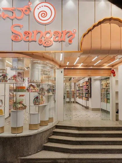 The storefront for Sangam Sweets in Bangalore, where we blended traditional Indian architectural elements with a modern retail experience. The multi-foliate arched entrance and fluted peach fascia guide customers inside. This design respects the brand's rich history while creating an inviting and contemporary street presence.