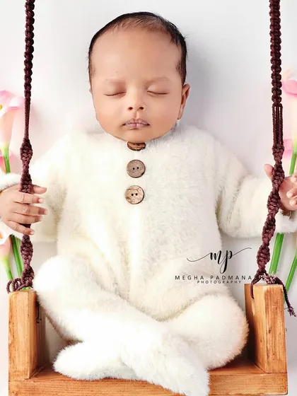 A baby enjoying a gentle rest on our custom-made miniature swing. This image demonstrates the variety of unique and safe props we bring to your home to create enchanting and memorable photographs.