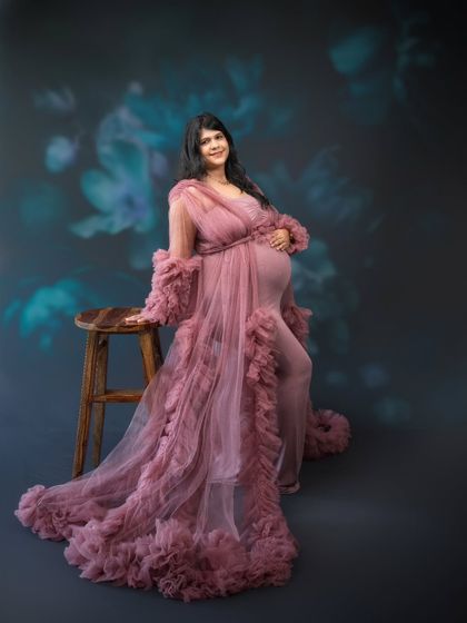 Embracing the gentle allure of motherhood with elegance and poise. This delicate, rosy gown wraps our client in an aura of warmth and tenderness.