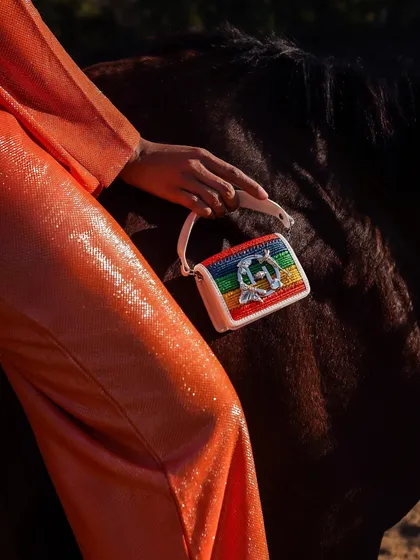 A detailed shot of a handbag against the rich, dark coat of a horse. The contrast in textures makes for a visually interesting and high-end commercial photograph.