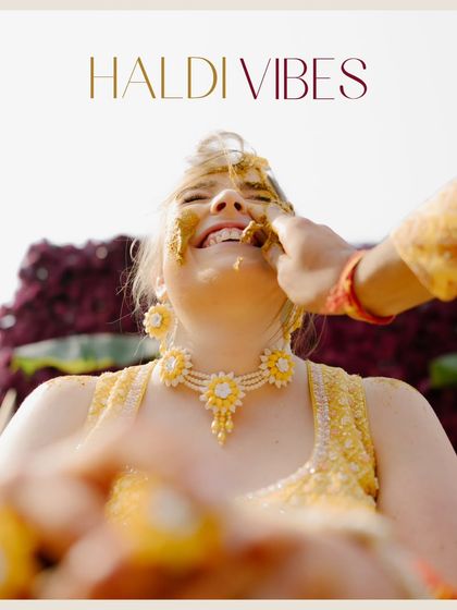 With "Haldi Vibes" text overlay, this image captures the bride's radiant laughter as turmeric is applied, a classic pre-wedding ritual photo.