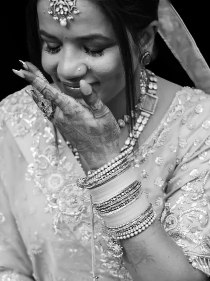A delicate black and white close-up of a bride's face, her hand gently touching her cheek.