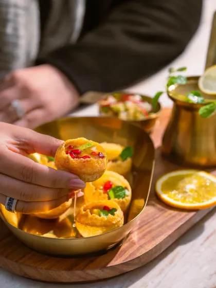 A lifestyle shot of someone enjoying Pani Puri at Camo, Noida, adding a human element to the food.
