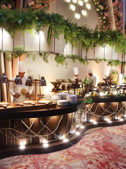 A beautifully lit, rustic-themed buffet station adorned with lush greenery. We believe that even the serving areas should be a feast for the eyes.