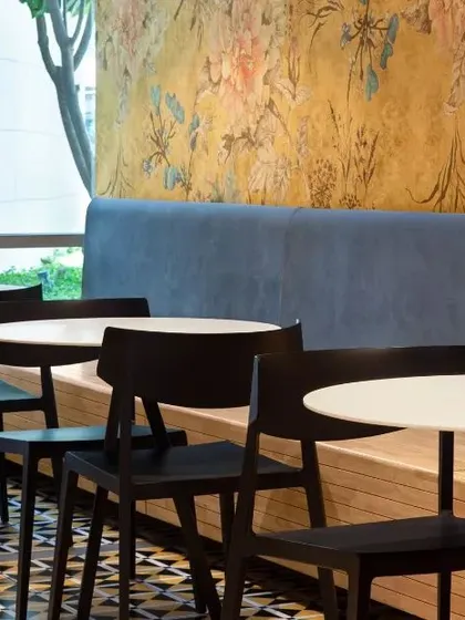 A bright and airy cafeteria space with floral wallpaper and patterned floor tiles. The large windows allow for ample natural light, creating a cheerful and refreshing break area.
