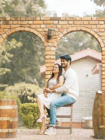 A relaxed and romantic pre-wedding portrait in a rustic, vineyard-style setting with brick arches and wooden barrels.