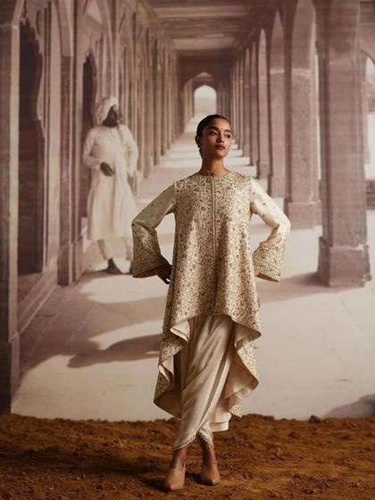 This look features an asymmetrical tunic with bell sleeves paired with dhoti pants. It's an example of fusion wear styling that is both contemporary and rooted in Indian silhouettes.