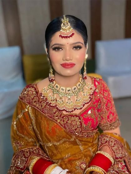 A front view of a bride with a sleek center-parted bun, adorned with a maang tikka. This classic bridal hairstyle is perfect for a traditional wedding ceremony.