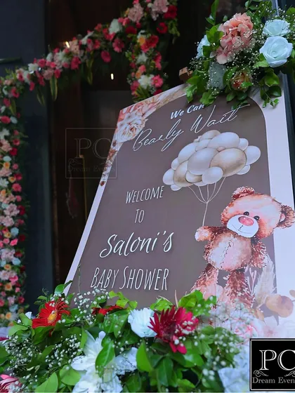 A personalized welcome sign for Saloni's baby shower, featuring the sweet "We Can Bearly Wait" theme. The sign is beautifully framed with fresh flowers, setting a warm and inviting tone.