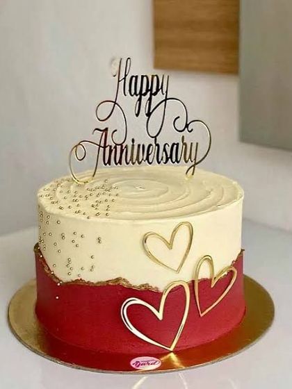 A client's photo of our red and white anniversary cake, featuring a torn-edge effect between the tiers and delicate gold sprinkles.