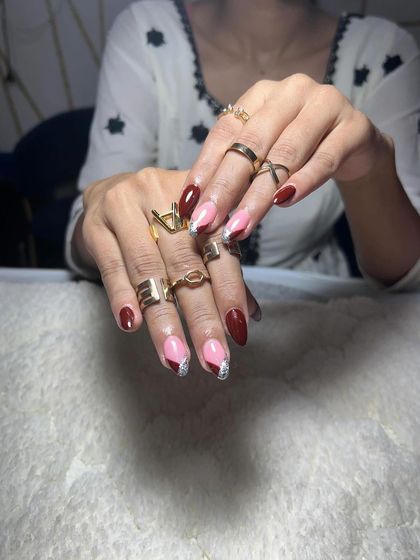 A stylish set with deep red nails and a glittery pink accent. The color combination is modern and chic.