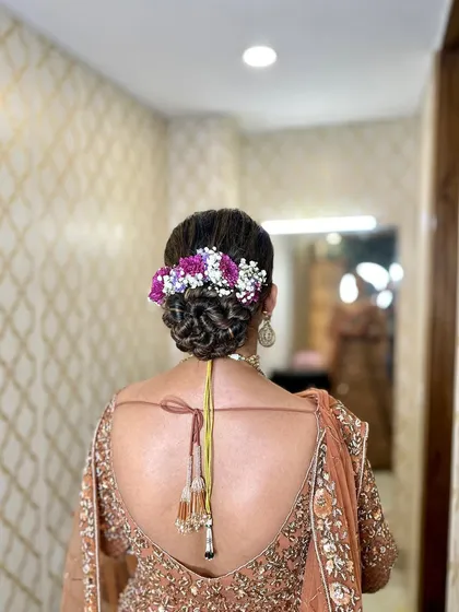 A final look at the bride's bun, adorned with a mix of purple and white fresh flowers for a vibrant touch.
