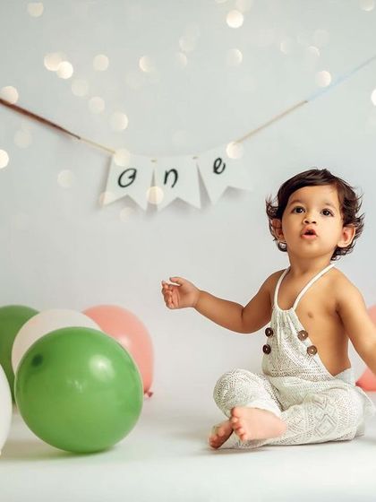 A simple and sweet first birthday portrait with a string of lights and a 'one' banner for a touch of celebration.