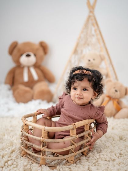 A cozy, rustic-themed sitter session with a teepee and teddy bears.