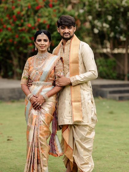 A classic couple's portrait. Her pastel-toned saree with a heavily worked blouse and his simple cream dhoti-kurta create a look of understated elegance.