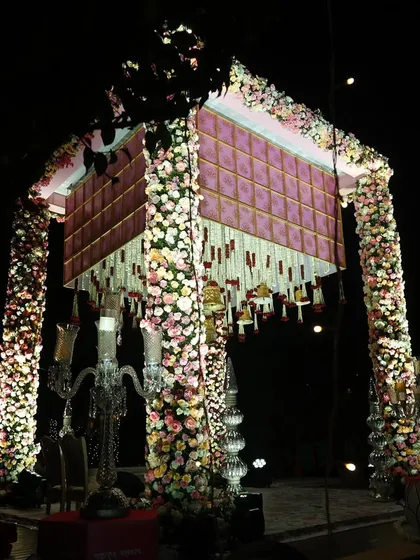 A magnificent floral mandap for a night ceremony. The structure is covered in pastel flowers, creating a breathtaking sight under the stars.
