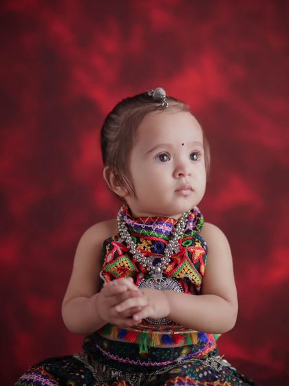 A close-up of our little Navratri queen. Her innocent expression and the details of her traditional jewelry are the focus of this adorable baby portrait.
