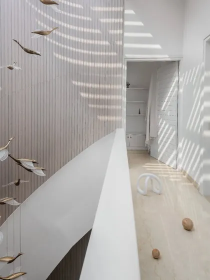 In this penthouse, I designed a helical staircase to be more than just a way to move between floors; it's a fluid, sculptural element. Bathed in light from a large skylight, its form contrasts with the clean, linear fluted wood wall, creating a focal point that is both art and architecture.