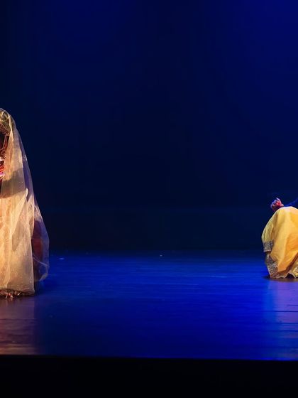 A quiet, contemplative moment between two characters in "KRISHNA". The vast, empty space on stage emphasizes their emotional connection and the importance of the scene.