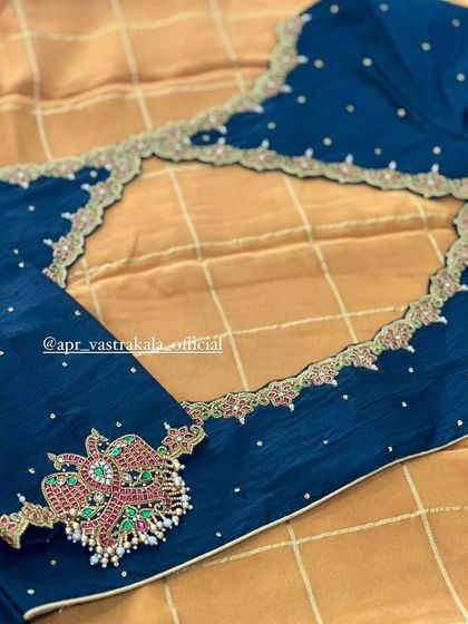 A deep teal blouse with a statement back cutout and a single large motif on the sleeve.