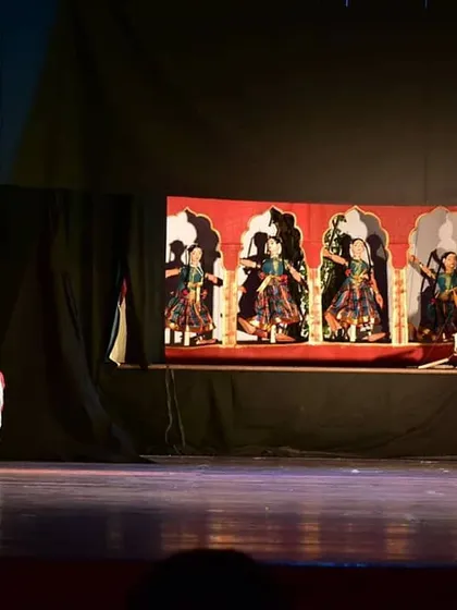 A moment of drama unfolds on stage, with the dancer's expression mirroring the narrative being enacted by the puppets.
