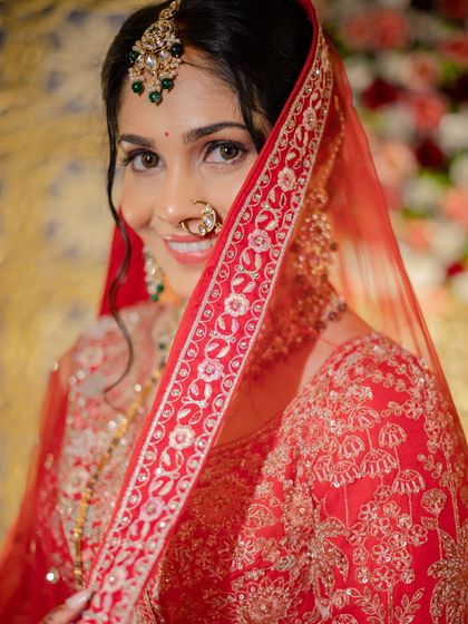 A playful peek from behind the veil. This shot captures the bride's happy smile and the intricate details of her red dupatta and jewelry.